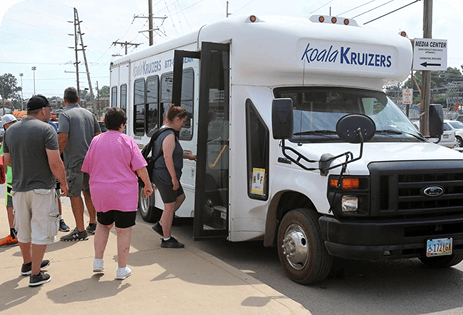 A group of people boards a white Koala Kruizers shuttle outdoors | Koala Kruizers